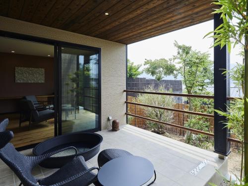 a patio with chairs and a table and a balcony at 宮島離れの宿 IBUKU -Miyajima Hanare no Yado IBUKU- in Miyajima