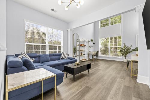a living room with a blue couch and two windows at 3BR Family Retreat with Modern Comforts in Charlotte