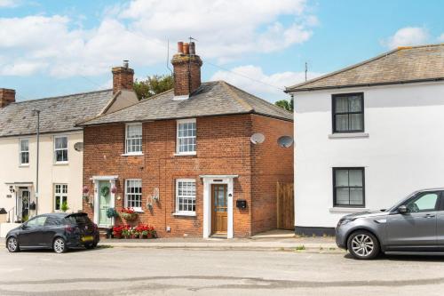 two cars parked in front of a brick house at Mill Dam Lake House in Saint Osyth