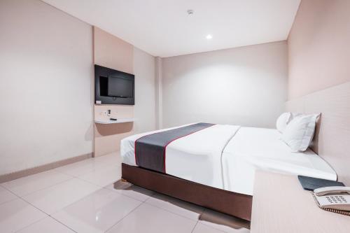 a white bedroom with a bed and a tv at Collection O Hotel Igloo in Bekasi