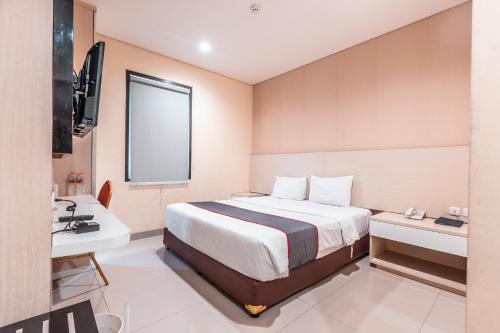 a hotel room with a bed and a television at Collection O Hotel Igloo in Bekasi