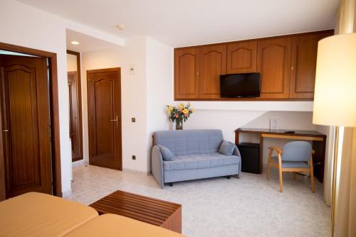 a living room with a blue chair and a table at Hotel Plaça in Sant Feliu de Guíxols