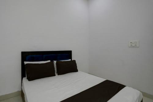a bed with black and white sheets and pillows at Hotel O KAVYA RESIDENCY in Alīgarh