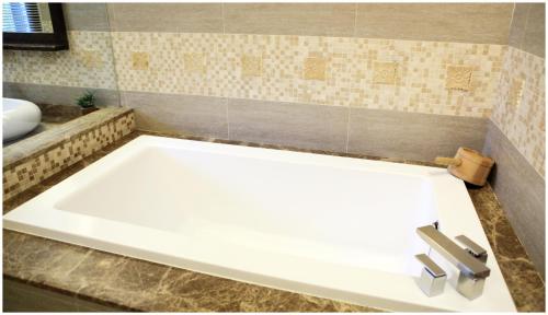 a white bath tub in a bathroom with a sink at Errantry Lodge & Studio in Hualien City