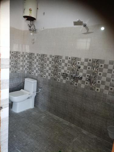 a bathroom with a toilet and a tile wall at Parvatiya Homestay in Mussoorie