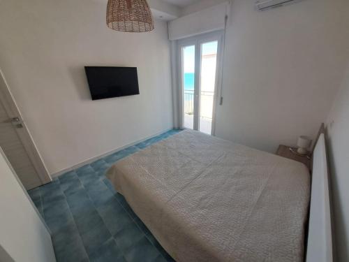 a white bedroom with a bed and a television at Sabina's House in Acciaroli