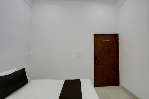 a room with a bed and a wooden door at Hotel O KAVYA RESIDENCY in Alīgarh