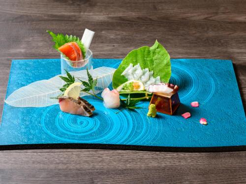 a blue plate with some food on a table at 宮島離れの宿 IBUKU -Miyajima Hanare no Yado IBUKU- in Miyajima
