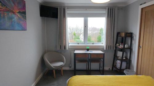a bedroom with a bed and a desk and a window at Innisfree Guest House in Fort William