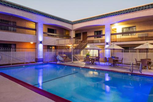 a pool in front of a hotel with tables and chairs at Days Inn & Suites by Wyndham Artesia in Artesia