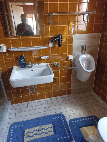 a man taking a picture of a bathroom with a sink and a urinal at Haus am Berg in Wertheim