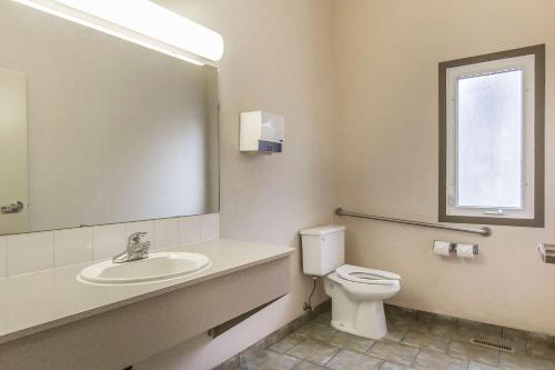 a bathroom with a toilet and a sink and a mirror at Econo Lodge Inn & Suites in Lethbridge