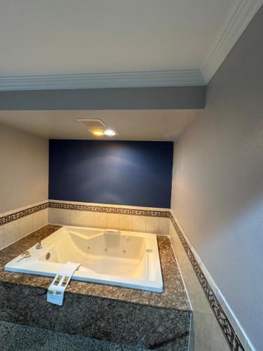 a bath tub in a room with a blue wall at Sunset Inn & Suites in Gardena