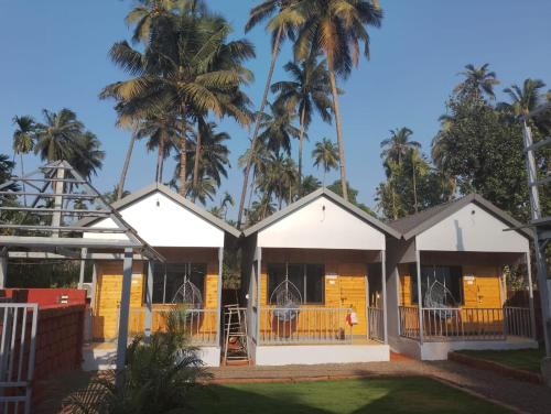 a house with palm trees in the background at Wantara resort in Diveagar
