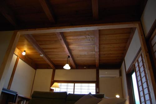 a living room with wooden ceilings and a couch at 一軒宿 百々 private house rental doudou in Mitoyo