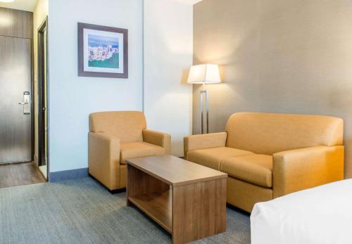 a hotel room with a bed and a chair and a table at Quality Hotel Dorval Aeroport in Dorval