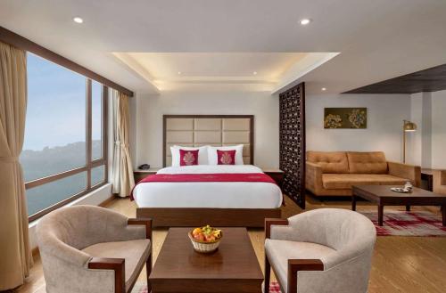 ガントクにあるRamada by Wyndham Gangtok Hotel & Casino Goldenのベッドと大きな窓があるホテルの部屋