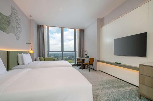a hotel room with two beds and a flat screen tv at Doubletree By Hilton Guang'An in Guang'an