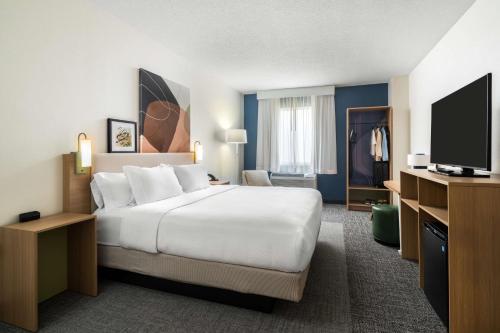 a hotel room with a bed and a flat screen tv at Spark by Hilton Opelousas in Opelousas