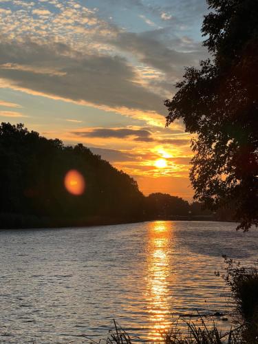 a sunset over a body of water with trees at Cozy apartment steps from the spa fountain in Poděbrady