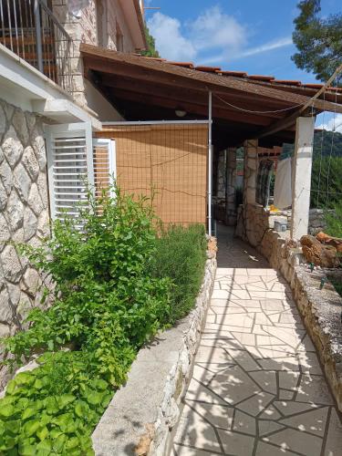 a house with a stone wall next to a walkway at Studio apartment Dragana in Sobra