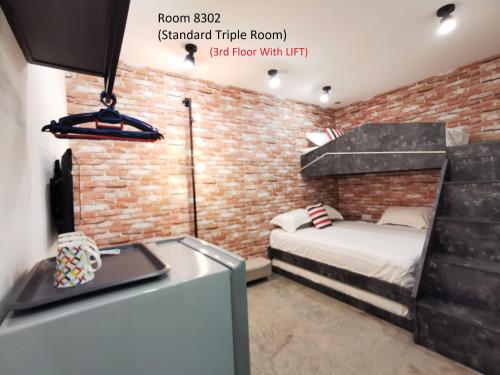 a room with a bed and a brick wall at Mwv Family Suite Room in Muar
