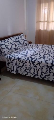 a bed with a black and white comforter on it at White home in Dodangoda