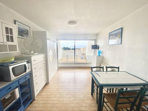 une petite cuisine avec une table et un micro-ondes dans l'établissement STUDIO CABINE 4 PERSONNES + PARKING, au Grau-du-Roi