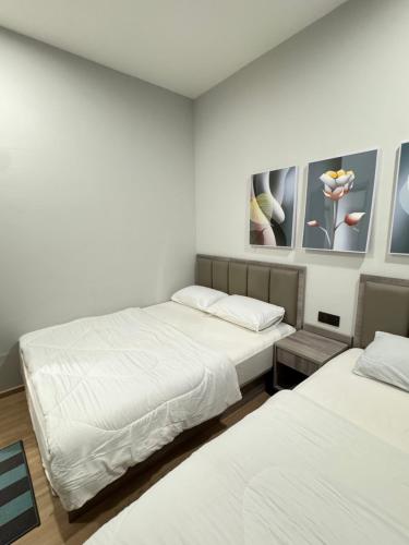 a room with two beds and two paintings on the wall at AYAAN PLATINUM Foosball Home at Quintet Apartment Free Parking in Tanah Rata