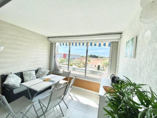 un salon avec une table et des chaises et une fenêtre dans l'établissement STUDIO CABINE 4 PERSONNES + GARAGE, au Grau-du-Roi