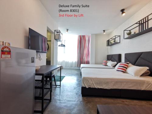 a hotel room with two beds and a desk at Mwv Family Suite Room in Muar