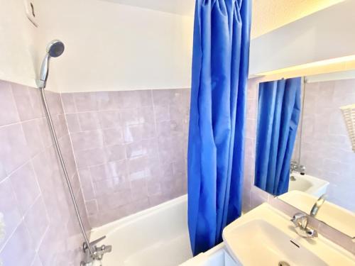 La salle de bains est pourvue d'un rideau de douche bleu et d'un lavabo. dans l'établissement APPARTEMENT 1 CHAMBRE ET PISCINE POUR 6 PERSONNES, au Grau-du-Roi