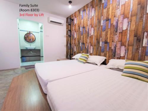 a bedroom with two beds and a wooden wall at Mwv Family Suite Room in Muar