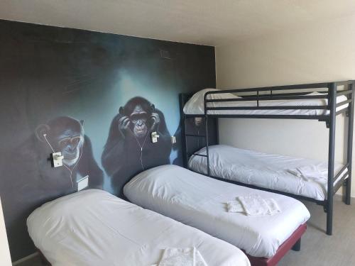 two bunk beds in a room with a mural of chimpanzees at Fasthotel in Jaux