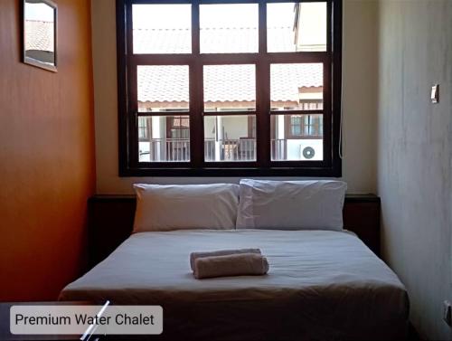 a bed with a towel on it in a room with a window at Alpine Premium Water Chalet 2 in Port Dickson