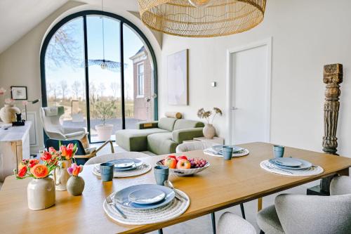 a living room with a wooden table and chairs at Statelan Logies, sfeervol en luxe ingericht vakantiehuis met 2 slaapkamers in het hart van friesland in Baardburen