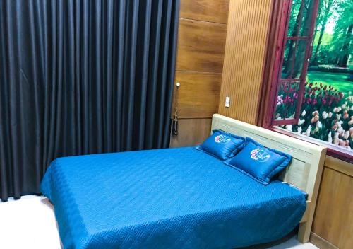 a bedroom with a bed with blue sheets and a window at Khách sạn Sông Hiếu in An Binh