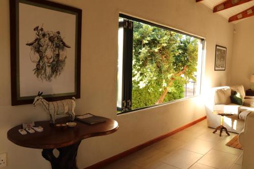 a living room with a table and a large window at The Goat House Farmstay in Nelspruit