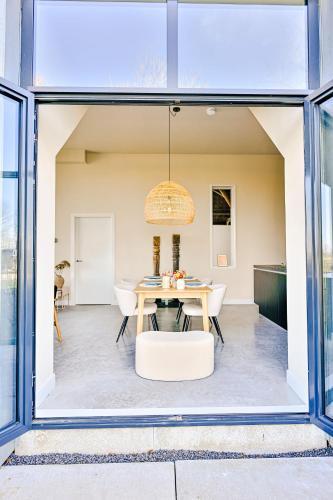 a dining room with a table and a window at Statelan Logies, sfeervol en luxe ingericht vakantiehuis met 2 slaapkamers in het hart van friesland in Baardburen
