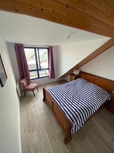 Un dormitorio con una cama, una silla y una ventana en Duplex 100m de la mer, en Larmor-Plage