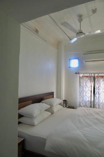 a bed with white sheets and pillows in a room at Dev Niwas - Heritage Hotel in Būndi
