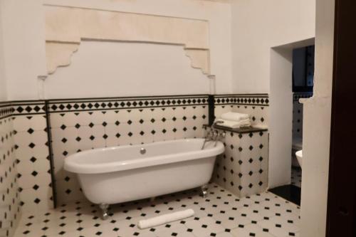 a bath tub in a bathroom with black and white tiles at Dev Niwas - Heritage Hotel in Būndi