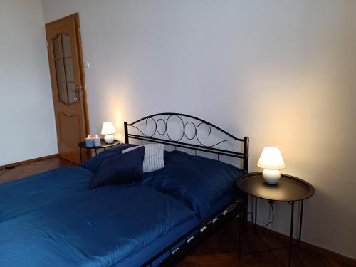 a bedroom with a blue bed with two tables at Apartmán Waldruh s terasou in Jalŭvčí