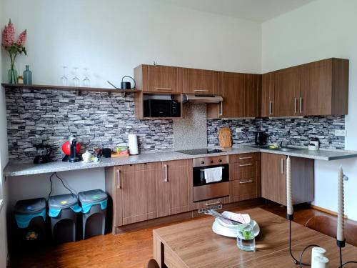 a kitchen with wooden cabinets and a brick wall at Apartmán Waldruh s terasou in Jalŭvčí