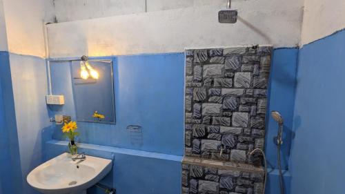 uma casa de banho azul com um lavatório e um chuveiro em Shenahi Homestay Hiriketiya em Dikwella