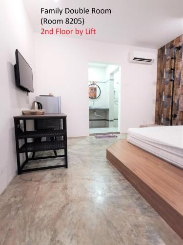 a bedroom with a bed and a desk and a television at Mwv Family Suite Room in Muar