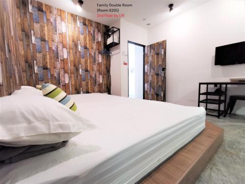 a bedroom with a white bed and a television at Mwv Family Suite Room in Muar