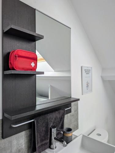 un sac rouge est assis sur une étagère dans une salle de bains dans l'établissement Gite du Persil - Meublé de Tourisme 3 étoiles, à Le Mesnil-Simon