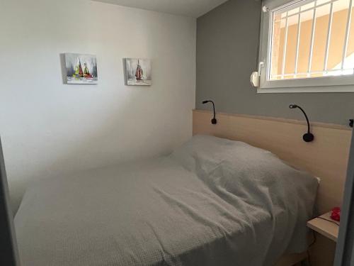 - une petite chambre avec un lit et deux photos sur le mur dans l'établissement Résidence Azureva - Richelieu, au Cap d'Agde