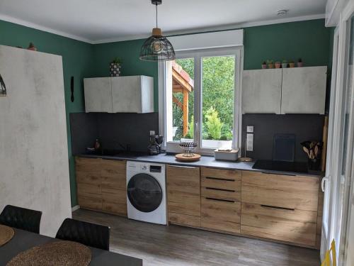une cuisine avec une machine à laver et une fenêtre dans l'établissement Le Cerisier - Proche Centre Village et Rivière, à Ruoms